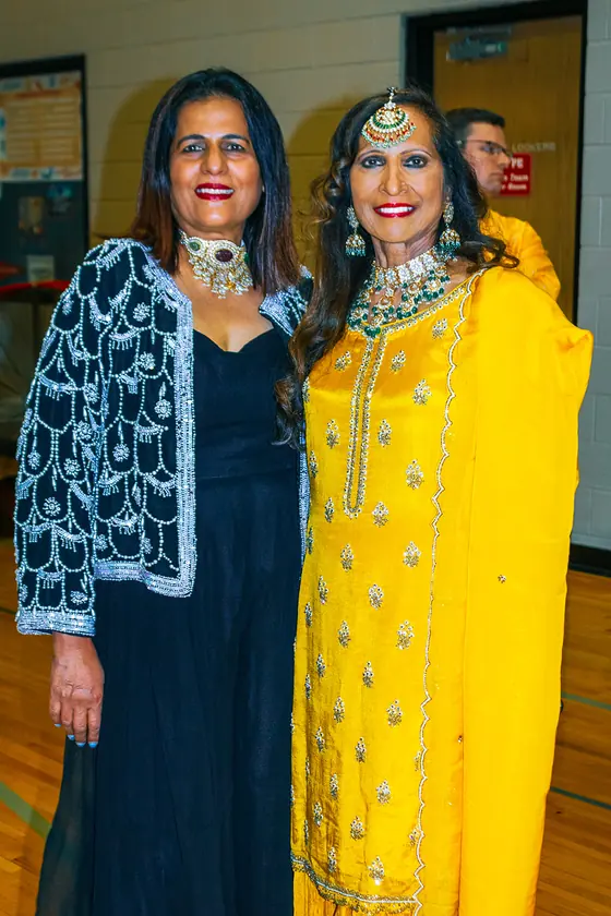 Two guests in embroidered blue and yellow Indian outfits at the festival