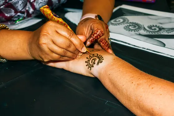 An artist applying a henna design to a guest's hand