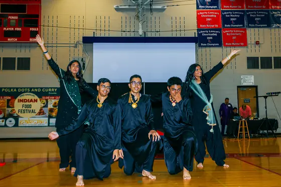 Dancers in teal costumes celebrating on the gymnasium floor