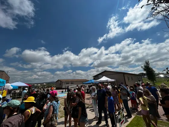 Festival-goers gathered outdoors beneath marquees on a bright summer day