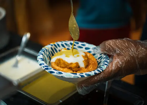 A vendor spooning fresh curry into a patterned bowl