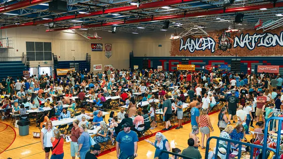 A packed gymnasium of festival guests seated for the performances