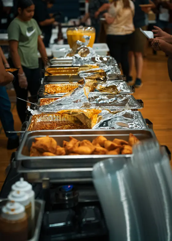 Chafing trays lined up along the buffet, filled with hot regional dishes