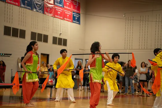 A group folk dance performance in bright green and yellow costumes