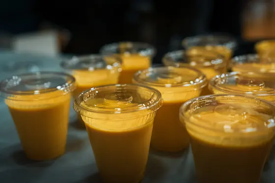 Cups of fresh mango lassi lined up on the counter