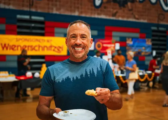 A guest smiling with a plate of samosa in the festival hall